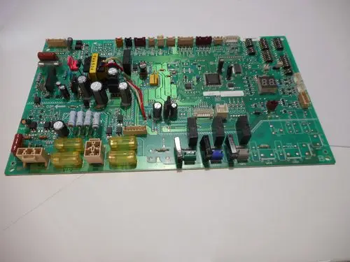 Platinenaufbau mit verschiedenen elektronischen Bauteilen und Verbindungen, gefertigt von Remeha. Sichtbare Kondensatoren, Widerstände und ein Display.